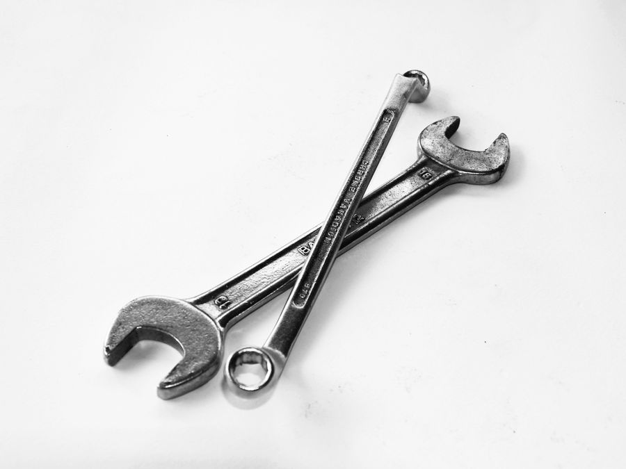 Two wrenches crossed on a plain surface.